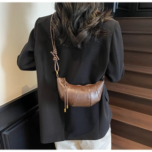 Detail showing back view of dark brown croissant crossbody bag worn by a model