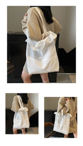 Close-up detail of white canvas tote bag with delicate lace stitching and pleated edges