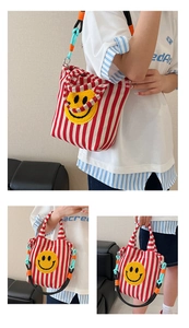 Détail du sac en toile à rayures rouges et blanches avec écusson brodé smiley jaune