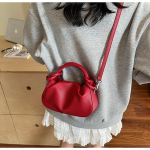 Detail of red lychee textured leather cloud bag with pleated design and metal hardware