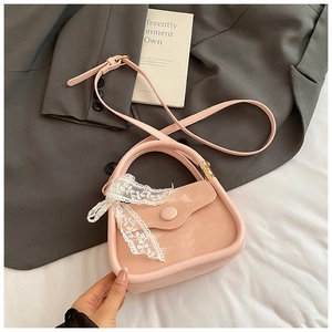 Détail d'un mini sac rose avec nœud en dentelle blanche et finition simili brillant