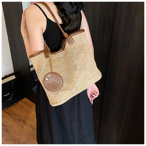 Close-up of woven straw tote bag featuring brown leather trim and slim shoulder straps