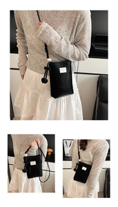 Detail of black mini shoulder bag with pearl woven strap and white bow label