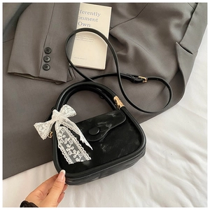 Détail du sac à main noir semi-circulaire avec nœud en dentelle et bandoulière