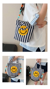 Détail du sac en toile à rayures bleues avec broderie smiley jaune et sangle colorée