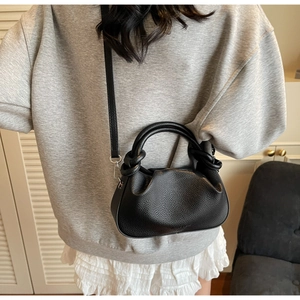 Detail of black cloud bag with knotted handle and lychee texture worn by a model