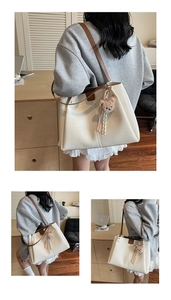Detail of cream crocodile textured tote bag with brown straps and plush bear charm