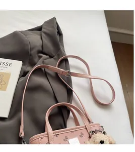 Détail d'un sac à main rose avec imprimés nœuds et breloque ours en peluche mignonne