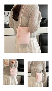 Detailed view of pink crossbody phone bag with pearl woven strap and bow accent