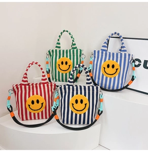 Détail de sacs fourre-tout rayés en toile avec patchs smiley jaunes et bandoulières