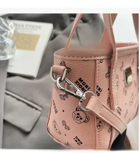 Gros plan d'un sac à main rose en cuir avec motif d'ours et détails de crochet argenté
