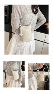 Detail of cream crossbody phone bag with heart charm and pearl decorative accents