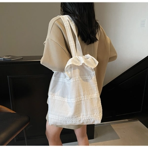 Close-up of white canvas tote bag with ruffled lace details and pleated texture