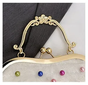 Dettaglio del manico floreale dorato e delle perle colorate su una borsa in pizzo bianco