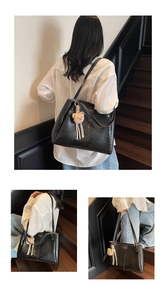 Detail of black crocodile texture tote bag with golden logo and plush bear charm