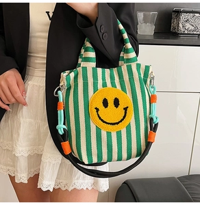 Détail du sac en toile rayé vert avec patch smiley jaune et bandoulière en corde colorée