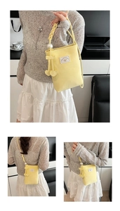 Detail of light yellow bucket bag with pearl handle and sweet heart-shaped charms