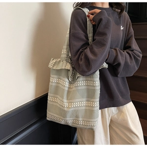 Side view of green and white plaid canvas tote bag showing large capacity on model