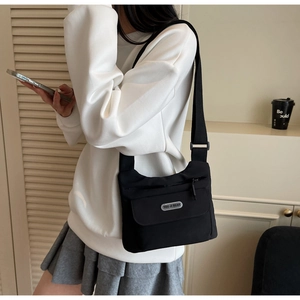 Dettaglio borsa a tracolla in nylon nero con design multitasche e cinghia regolabile