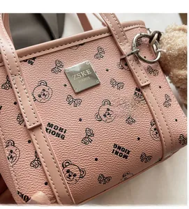Détail du sac à main en cuir rose avec imprimé ours et pompon en fourrure douce