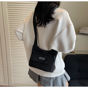 Dettaglio della borsa a tracolla in nylon nero con logo indossata da un modello