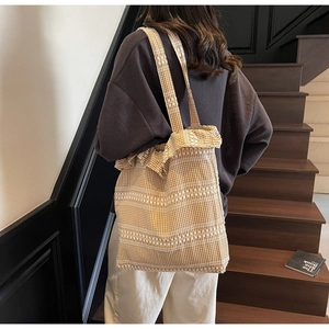 Detail of yellow checkered canvas tote bag featuring lace trim and floral embroidery