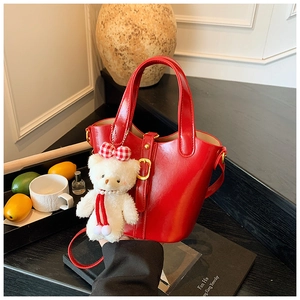 Vue détaillée d'un sac seau rouge vif avec un charmant ours en peluche et fermoir doré
