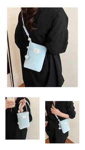 Detail of light blue mini phone bag with pearl strap decoration and heart charms
