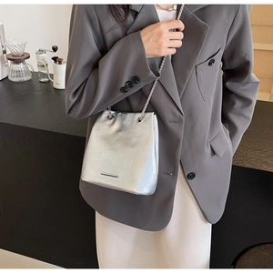 Detail of silver metallic leather handbag with chain strap and sleek metal accent bar