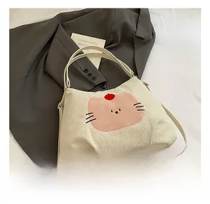 Close-up of cream corduroy tote bag featuring pink cat embroidery and slim handles