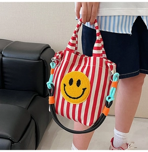 Vue détaillée du sac cabas en toile à rayures rouges avec un visage souriant brodé jaune