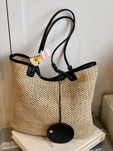Large hand-woven straw tote bag with black leather trim and long shoulder straps for beach use