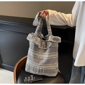 Detail of checkered canvas tote bag with ruffled lace trim and white textured bands