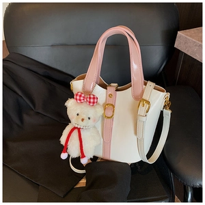 Détail du sac seau crème avec anses roses, finitions dorées et breloque ours en peluche