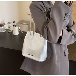 Close-up of metallic silver bucket bag featuring chain strap and textured soft leather finish