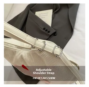 Detail showing adjustable strap on white corduroy tote bag with metal hardware