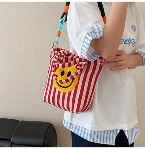 Détail du sac en toile rayé rouge et blanc avec écusson smiley jaune brodé