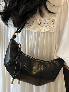 Minimalist black quilted croissant shoulder bag with knotted strap and gold hardware