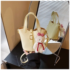 Détail du sac seau crème avec fermoirs dorés et décoration de petit ours en peluche