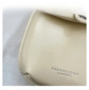 Macro detail of cream leather bag featuring silver embossed text and premium stitching