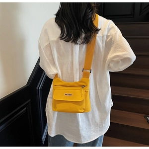 Dettaglio di una borsa a tracolla in nylon giallo acceso con tracolla regolabile sul modello