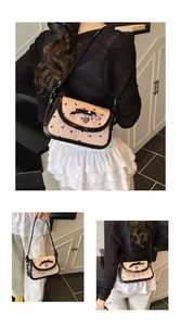 Detail of pink embroidered bow bag with heart pendant and ruffled fabric texture
