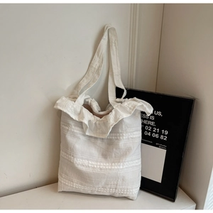 Close-up of white canvas tote bag with ruffled edges and detailed ribbed fabric texture