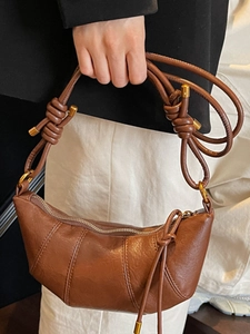 Minimalist brown leather croissant shoulder bag with quilted details and knotted strap