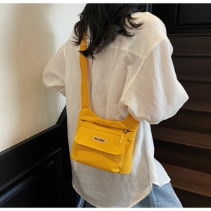 Dettaglio di una borsa a tracolla in nylon giallo con cinturino regolabile e zip