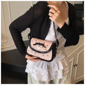 Detailed shot of a pink textured fabric underarm bag with black bow and silver heart charm