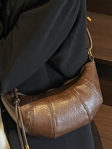 Minimalist dark brown croissant crossbody bag with wax finish and knotted strap detail