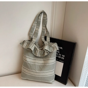 Detail of green gingham canvas tote bag with ruffled edges and lace woven patterns