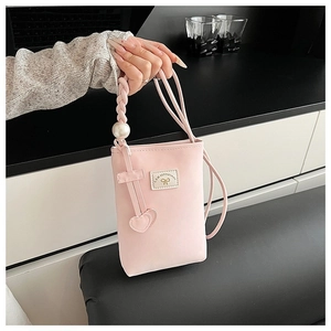 Detail of pink crossbody phone bag with pearl handle and heart pendants
