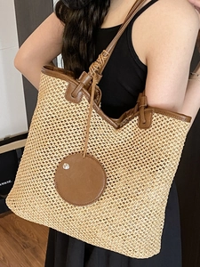 Large beige woven straw tote bag with brown leather handles for summer beach vacations